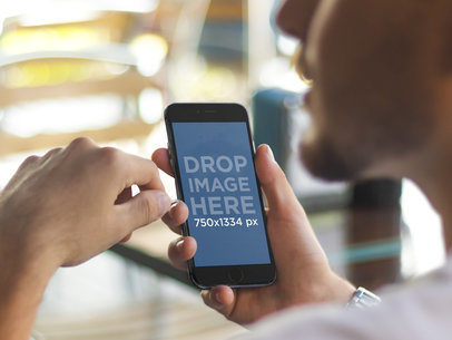 Mockup of Young Man Using Black iPhone 6 at Restaurant