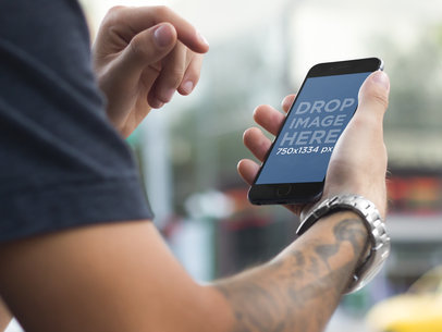 Tattooed Young Man in Urban Setting Using an iPhone Mockup