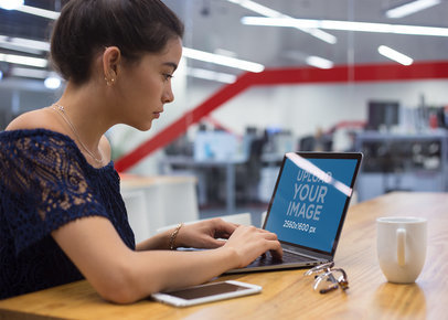 Mockup of a Woman Working with a MacBook on a Wooden Desk