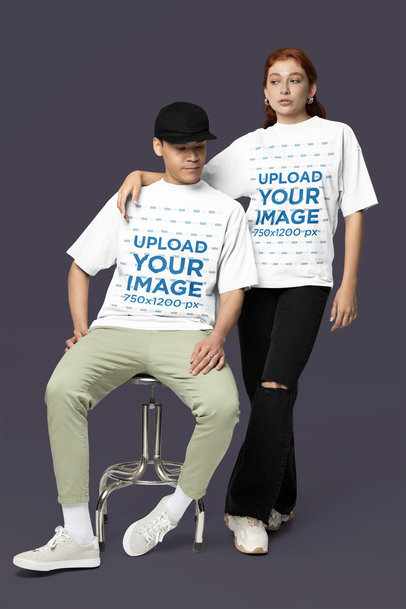 Oversized T-Shirt Mockup of a Woman Posing With a Man in a Studio With a Customizable Backdrop