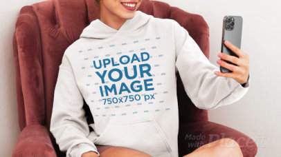 Gildan Hoodie Video Featuring a Cropped-Face Woman Sitting on a Couch Taking a Selfie