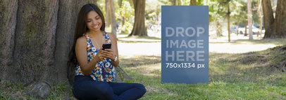 Mockup of a Woman Using Her Black iPhone 6 Under a Tree
