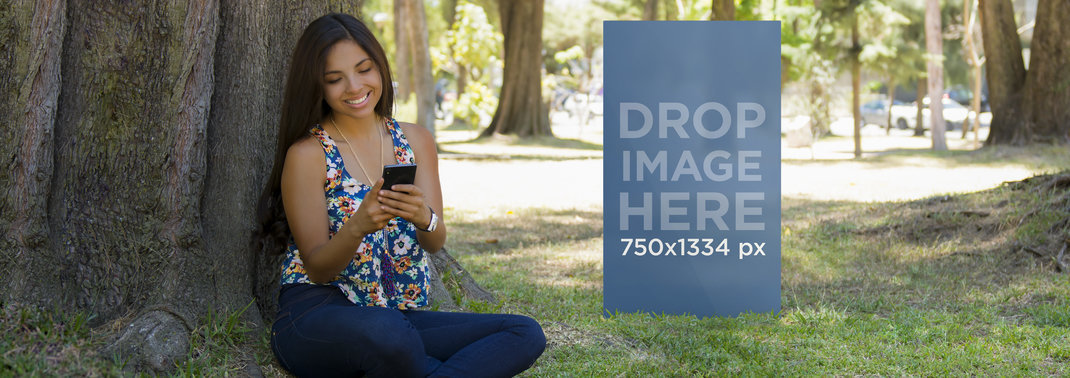 Mockup of a Woman Using Her Black iPhone 6 Under a Tree