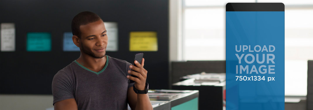 Mockup of Young Man Using his Smartphone at a Creative Office