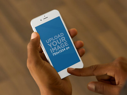 Mockup of a Man Using iPhone 6 Over Wooden Floor Background 