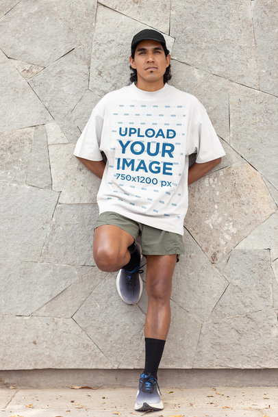 Oversized T-Shirt Mockup Featuring a Runner Man Leaning Against a Rock Wall