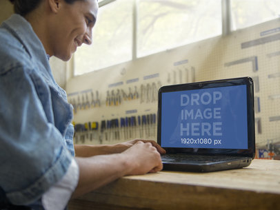 Young Man Using his HP Laptop at an Industrial Workshop 