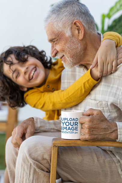 Coffee Mug Mockup Featuring a Smiling Senior Man Being Hugged by His Grandson m39436