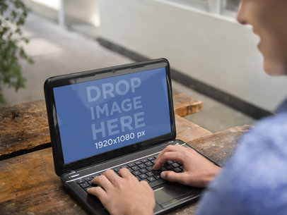 Mockup of a Young Man Using his HP Laptop on an Outdoor Table