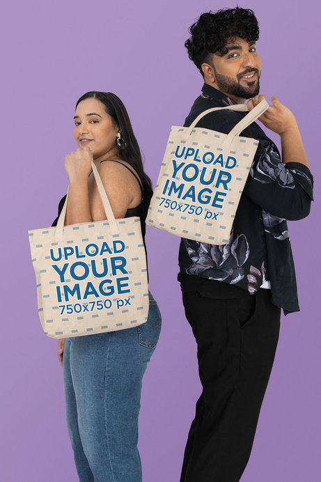 Mockup Featuring a Man and a Woman Carrying Matching Tote Bags in a Studio
