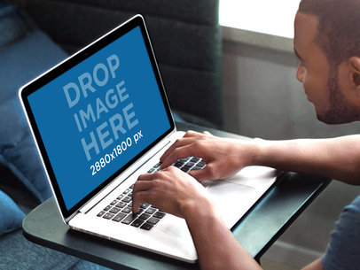 Mockup of a Young Man Working on a Macbook Pro at a Creative Office
