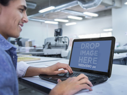 Mockup of aYoung Man in an Industrial Workshop Using a Black HP Laptop