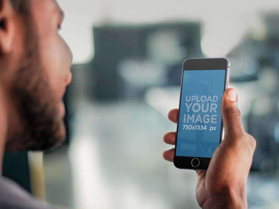 Mockup of a Young Man Using a Black iPhone 6 Smartphone