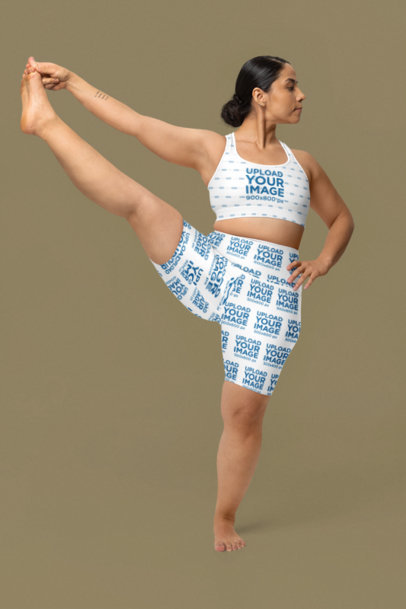 Sports Bra and Yoga High-Waisted Shorts Mockup of a Woman Stretching Her Leg in a Studio