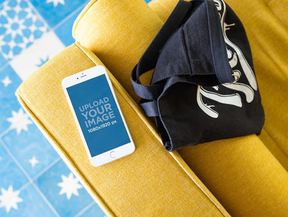 Silver iPhone 8 Plus Mockup Lying on a Yellow Sofa Near a Bag
