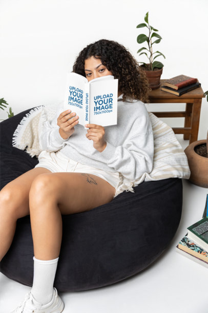 Book Mockup Featuring a Serious Curly-Haired Woman Reading on a Bean Bag Chair m40288
