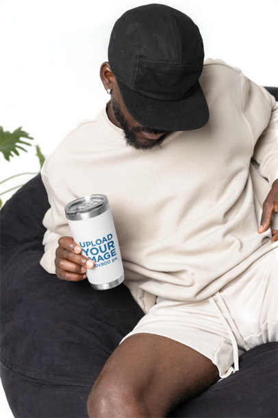 Travel Mug Mockup Featuring a Bearded Man Sitting on a Bean Bag Chair m40306