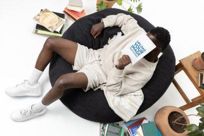 Print Mockup of a Man Hiding Behind a Book While Sitting in a Bean Bag Chair m40287