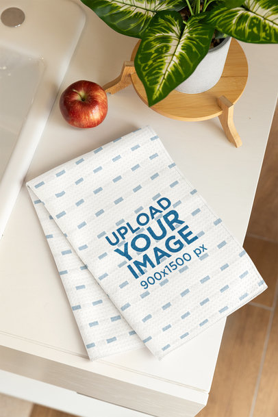 Home Decor Mockup Featuring a Mircrofiber Tea Towel Placed on a Table With a Plant and an Apple m40747