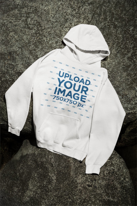Mockup Featuring a Gildan Pullover Hoodie Flat Laid over a Rock