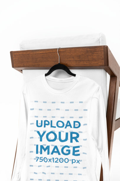 Mockup of a Bella Canvas Long-Sleeve Tee Hanging From a Chair Against a White Backdrop m39758