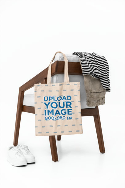 Mockup of a Sublimated Tote Bag Placed on a Wooden Chair With Other Garments m39782