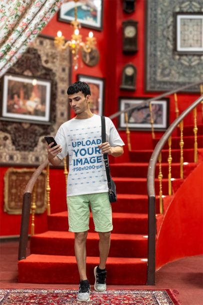 Blinkstore T-Shirt Mockup Featuring a Gen-Z Man Checking His Phone in a Red Room
