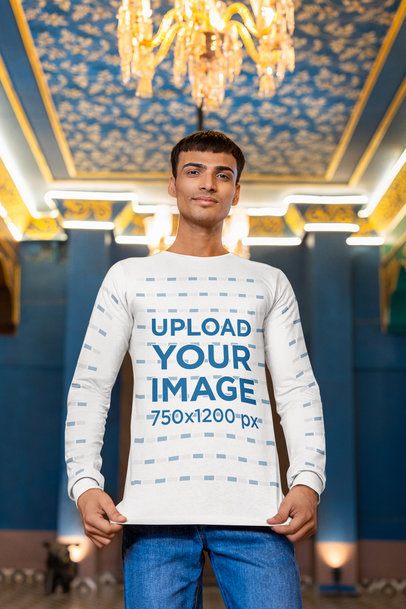 Mockup of a Gen-Z Man Wearing a Bella Canvas Long Sleeve Tee Under a Chandelier