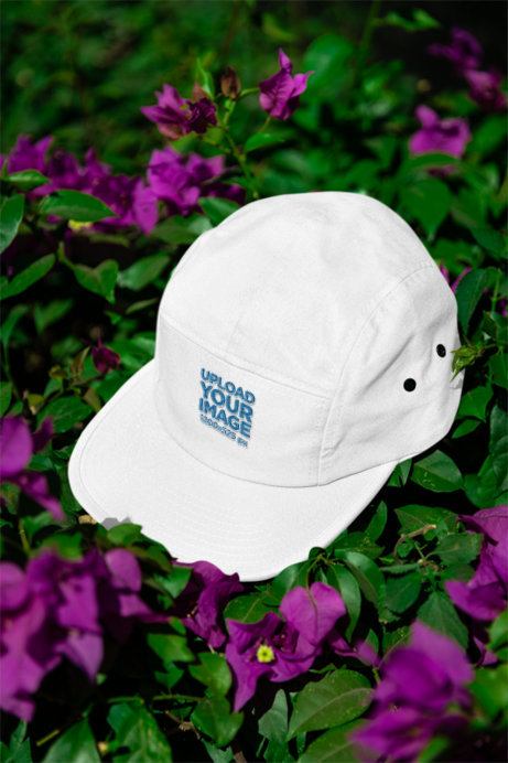 Mockup Featuring a Yupoong Panel Cap Placed over Leaves and Flowers