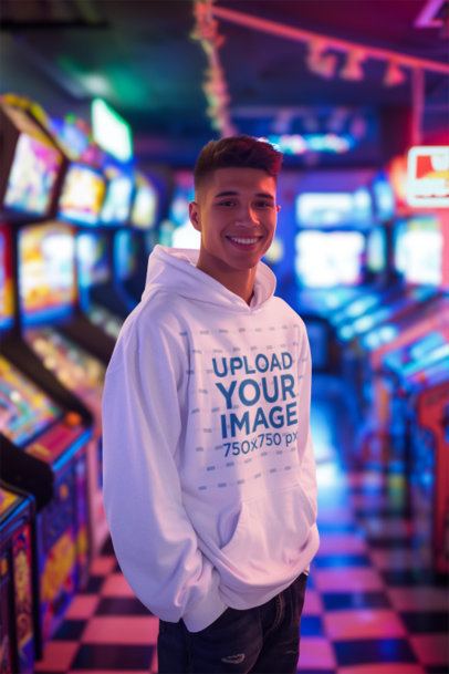 Mockup Featuring a Smiling Man Generated by AI Wearing a Pullover Hoodie in an Arcade