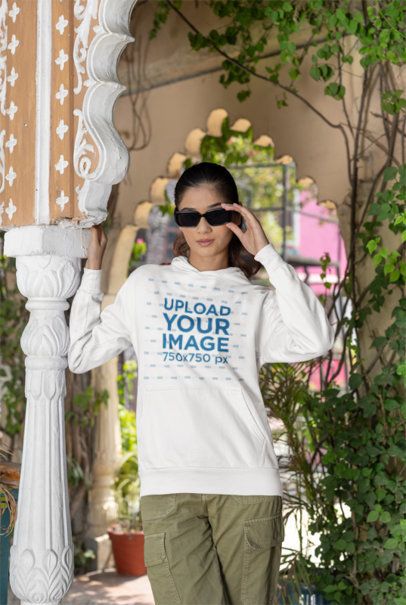 Gildan Pullover Hoodie Mockup of a Gen Z Woman Standing With Dark Sunglasses in a Balcony m40973