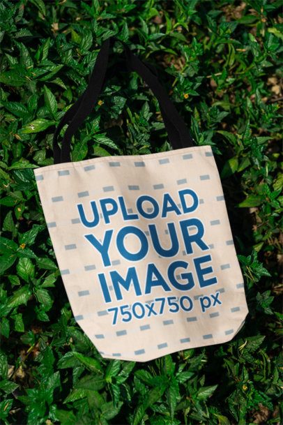 Mockup of a Tote Bag Flat Laid on a Bed of Green Leaves m39857