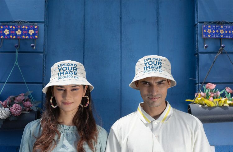 Adorazone Bucket Hat Mockup Featuring a Gen-Z Couple Posing Against a Blue Wall
