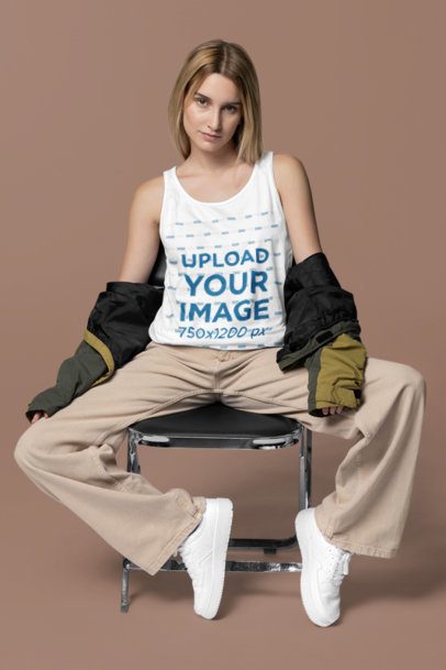 Studio Mockup of a Woman Wearing a Bella Canvas Tank Top While Sitting on a Chair