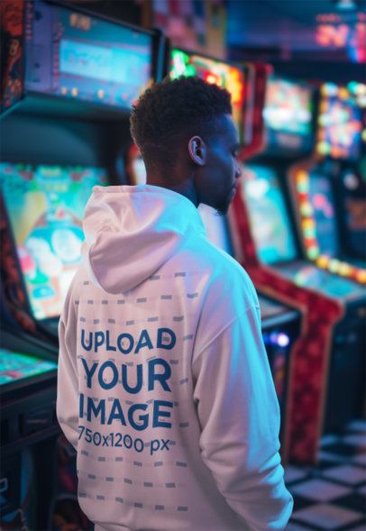 AI-Created Mockup Featuring a Man Wearing a Hoodie in an Arcade Room