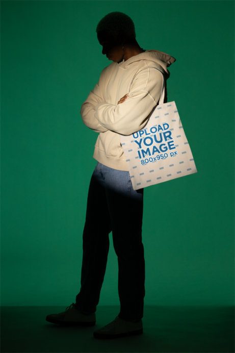 Mockup Featuring a Man Carrying a Tote Bag in the Spotlight of a Studio
