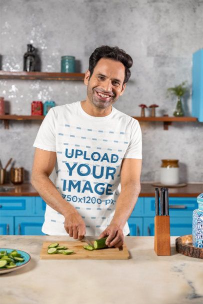 Scott International T-Shirt Mockup Featuring a Happy Man Chopping a Cucumber in the Kitchen