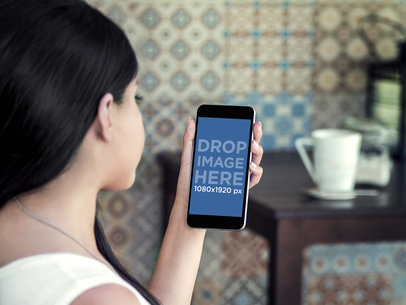 Mockup of a Girl Using Her iPhone 6 Plus Featuring a Colorful Tile Wall
