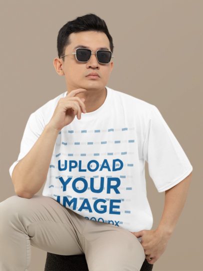 T-Shirt Mockup of a Man Wearing Sunglasses in a Studio with a Customizable Background