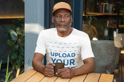 Bella Canvas T-Shirt Mockup of a Serious Senior Man Sitting in a Restaurant