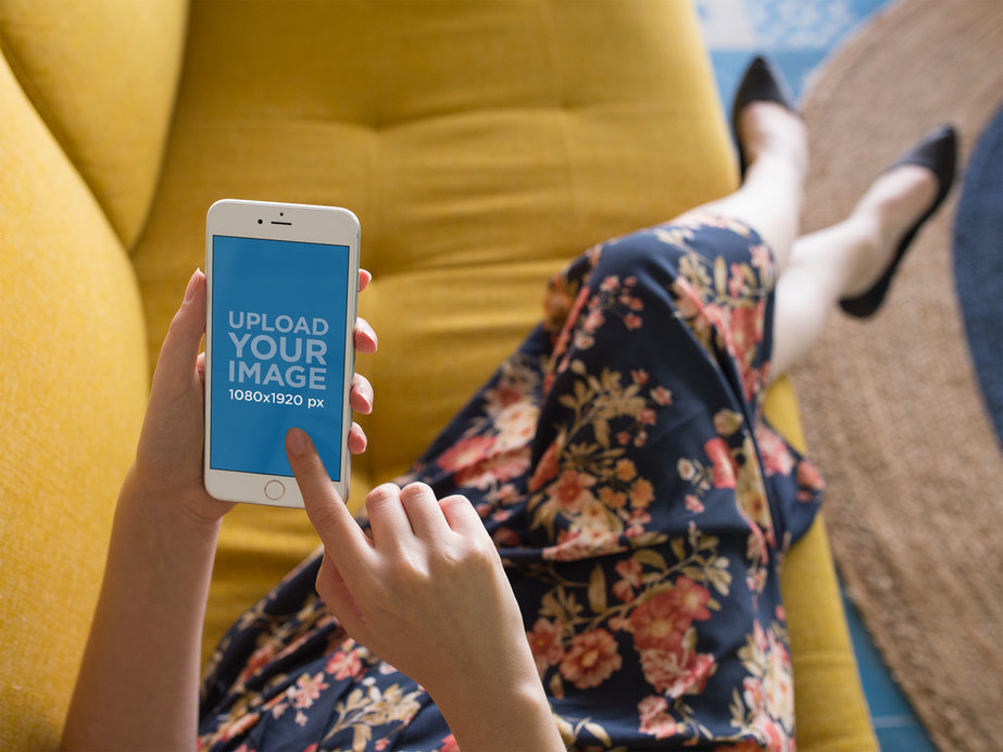 Silver iPhone Mockup of a Woman Lying on a Mustard Sofa