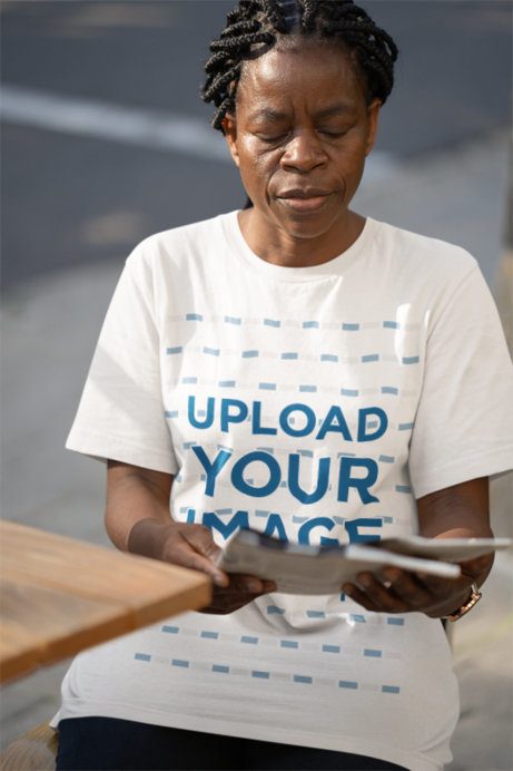 Bella Canvas T-Shirt Mockup Featuring a Senior Woman Reading a Newspaper