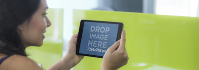 Young Lady Using a Black iPad on Vibrant Green Backdrop