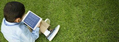 Mockup Template of a Young Boy Using an iPad While at the Garden