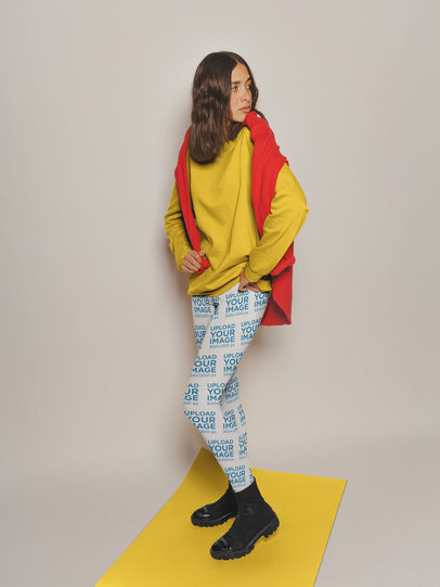 Mockup of a Shy Woman Wearing Leggings and a Sweater Standing on a Pasteboard