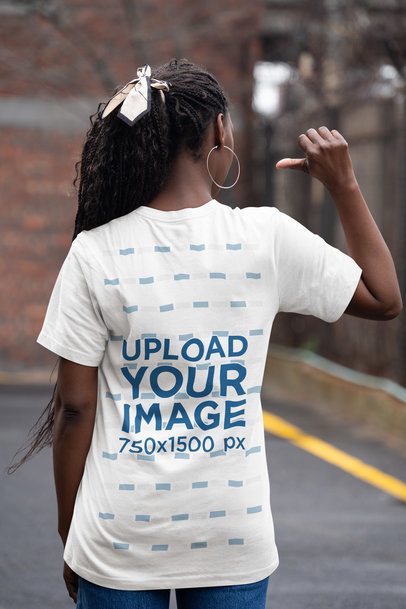Back-View Mockup of a Woman on a Street Pointing at Her New Bella Canvas T-Shirt 