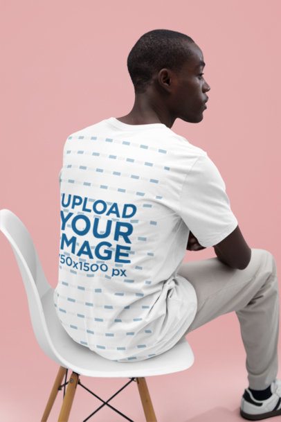 Back-View Bella Canvas T-Shirt Mockup of a Man Sitting on a Chair in a Studio