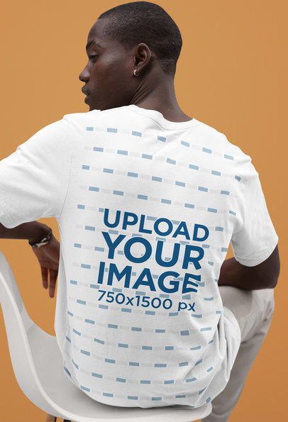 Back-View Bella Canvas Tee Mockup of a Man Sitting on a Chair in a Studio