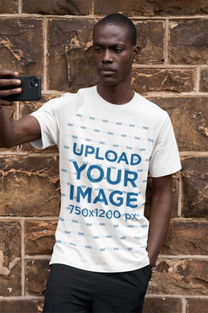 Bella Canvas Tee Mockup Featuring a Man Taking a Selfie by a Brick Wall