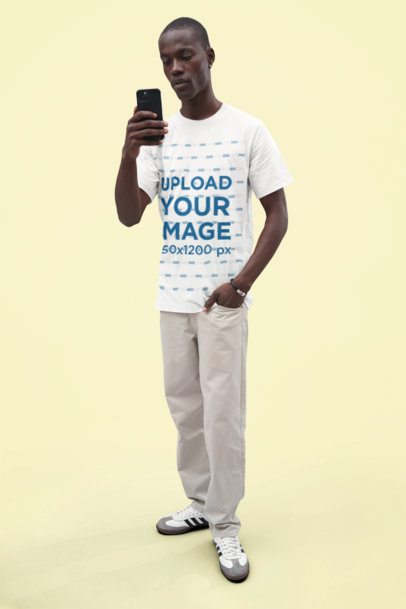 Bella Canvas Tee Mockup Featuring a Man Taking a Picture with His Smartphone in a Studio